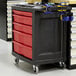 A black and red Rubbermaid TradeMaster mobile work center with 5 drawers.