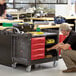 A man looking at a black Rubbermaid TradeMaster cart with drawers and a cabinet.