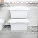 A metal shelf with a stack of white plastic food storage containers.