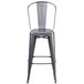 A silver metal bar stool with a vertical slat back and a drain hole seat.