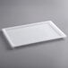 A white plastic lid on a gray surface over a white plastic tray.