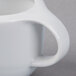 A close up of a Schonwald white porcelain sauce boat with a handle.