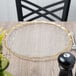 A Charge It by Jay clear glass charger plate with a gold rim on a table.