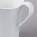 A close-up of a Schonwald white porcelain creamer on a white surface.