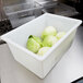 A white Carlisle food storage box filled with cabbages on a counter.