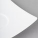 A close-up of a Schonwald white porcelain saucer with a curved edge.
