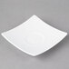 A Schonwald white square porcelain saucer on a gray surface.