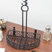 A black wrought iron half round condiment caddy with a card holder on a wood surface.