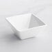 An Acopa bright white square porcelain bowl on a white surface.