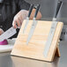 A person cutting a knife on a Mercer Culinary Z&#252;M&#174; rubberwood board.