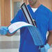 A man in blue scrubs using a Rubbermaid blue microfiber wet mop pad with hook and loop closure.