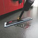 A Rubbermaid Light Commercial Spray Mop with a handle cleaning the floor with a water spray.