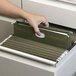 A hand opening a file drawer with Smead green hanging file folders inside.