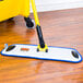 A Rubbermaid blue and white microfiber mop pad on a wood floor.
