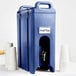 A navy blue plastic Cambro insulated beverage dispenser with a metal lid and faucet.