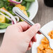 A hand holding a Libbey Cortland stainless steel dinner fork over a bowl of pasta and salad.