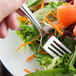 A Libbey stainless steel salad fork spearing a salad on a plate.