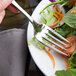 A Libbey stainless steel salad fork in a plate of salad.