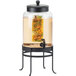 A Cal-Mil black glass beverage dispenser with an infusion chamber filled with fruit and flowers.
