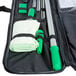 A black bag with a black strap and green and white tools inside.