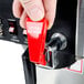 A person's finger pressing a red switch on a Bloomfield automatic coffee brewer.