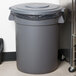 A Carlisle grey trash can lid on a grey trash can.