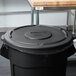 A Rubbermaid black trash can with a plastic lid.