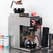 A Bunn automatic coffee maker with a coffee pot and cups on a counter.