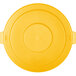 A yellow flat round lid with handles for a Carlisle Bronco trash can.