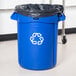 A blue Rubbermaid Brute recycling can with a black lid and recycling symbol.
