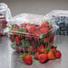 A clear plastic vented container holding strawberries.