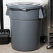 A Carlisle grey trash can lid on a grey trash can.