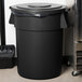 A Carlisle black round trash can lid on a black trash can.