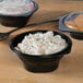 Two Fabri-Kal black plastic SideKicks bowls filled with food.