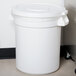 A white Carlisle Bronco trash can lid on a white plastic trash can.