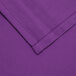 A purple square cloth table cover with a white hem.
