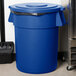 A blue Carlisle Bronco trash can lid with a black handle.