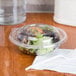 A plastic container of salad with a clear plastic dome lid.