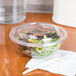 A salad in a Sabert clear plastic bowl with a clear plastic dome lid.
