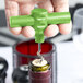 A person using a Franmara green plastic pocket corkscrew to open a wine bottle.
