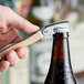 A person using a Laguiole Waiter's Corkscrew with beechwood handle to open a brown bottle on a bar counter.
