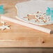 A Thunder Group wood Asian rolling pin and dough with stars cut out on a wooden surface.
