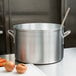 A large Vollrath silver sauce pot with carrots and onions cooking inside.