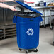 A woman using a blue Rubbermaid recycling can to recycle a tin can.