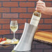 A hand pouring wine into a silver American Metalcraft wine cooler on a table.