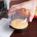 A hand using a Fabri-Kal plastic lid to cover a container of cheese dip.