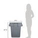 A woman standing next to a large grey Rubbermaid commercial trash can.
