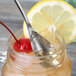 A Chef & Sommelier stainless steel iced tea spoon in a glass with a cherry and a lemon.