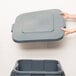 A person's hands holding a grey rectangular Rubbermaid Brute lid