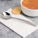 A Chef & Sommelier stainless steel soup spoon in a bowl of soup with crackers.